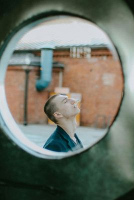 A man smokes in an urban outdoor setting, viewed through a circular frame depicting stress relief.